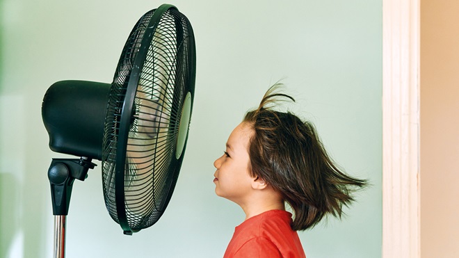 child cooling down in front of a pedestal fan